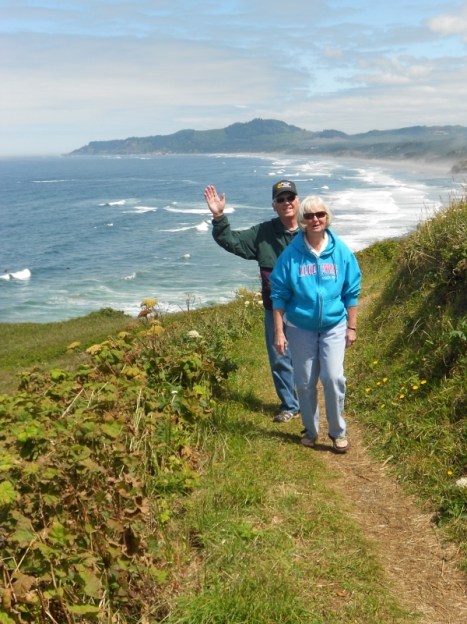 Couple hiking up hill with ocean in background