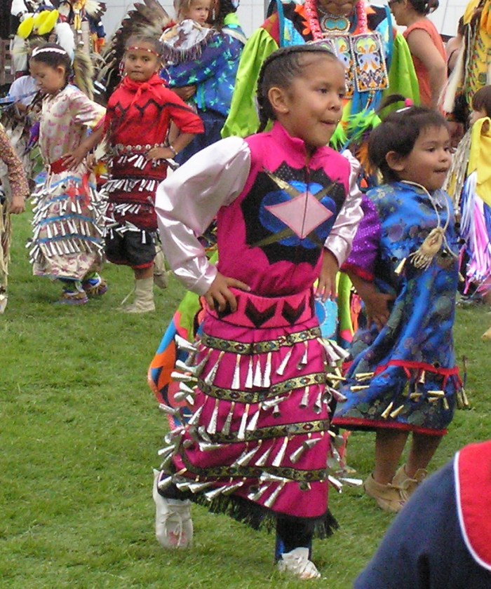Young girls wearing colorful dresses with bells on them